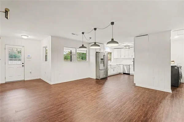 a view of a kitchen with refrigerator and an empty room