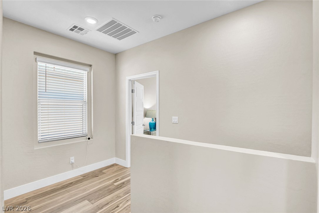 9688 Rankin Rdg Court Las Vegas, NV 89178 - Photo 25 of 53 A window-lit hallway with natural wood-look flooring connects various living spaces.