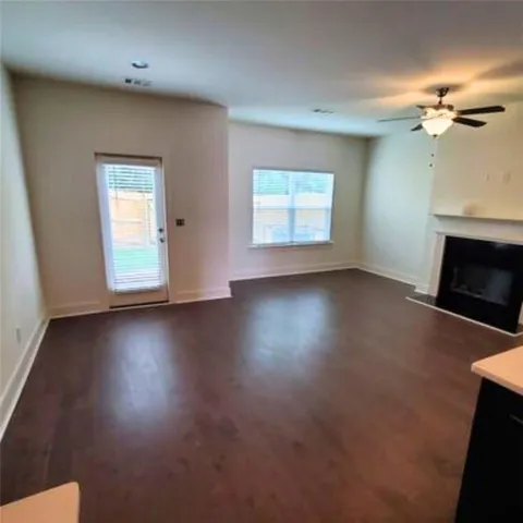 an empty room with windows fireplace and wooden floor