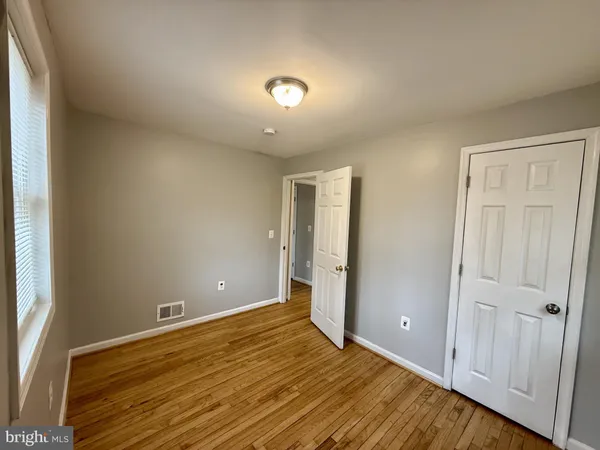 a view of an empty room with wooden floor and closet