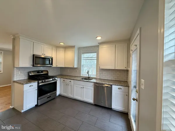 a kitchen with stainless steel appliances granite countertop a stove top oven a sink and dishwasher a refrigerator with wooden floor