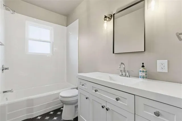 a bathroom with a granite countertop sink a toilet and a bathtub