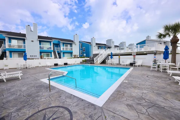 a view of a swimming pool with a lounge chairs in front of house