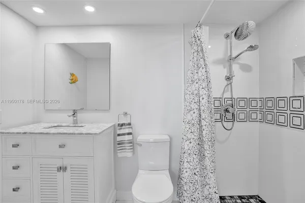 a bathroom with a granite countertop sink a toilet and shower