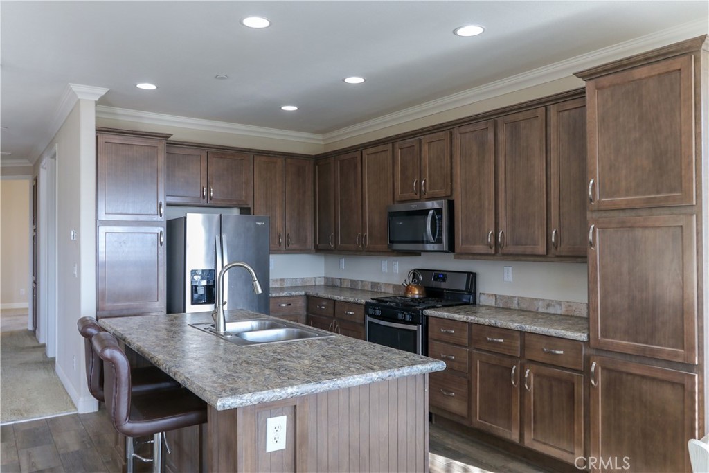 24000 Oak Cir Drive Wildomar, CA 92595 - Photo 6 of 22 a kitchen with kitchen island granite countertop wooden cabinets a sink a stove a refrigerator and island