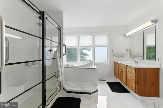 a bathroom with a sink a toilet a mirror a vanity and bathtub