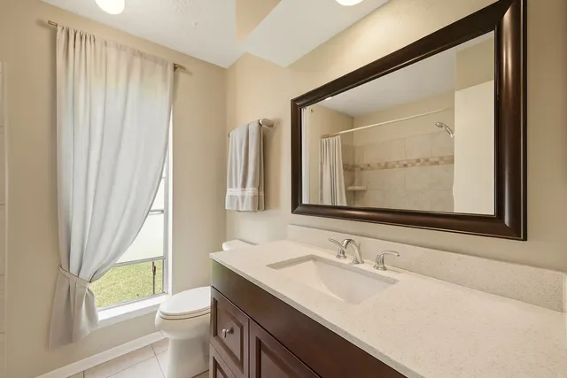 a bathroom with a granite countertop sink toilet and a mirror