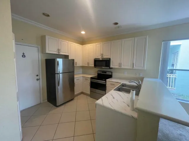 a kitchen with a refrigerator a microwave a sink and cabinets