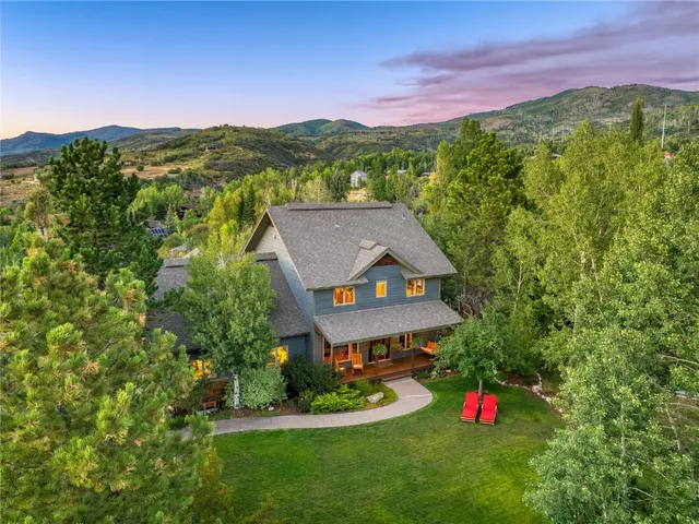 a view of a big house with a big yard and large trees