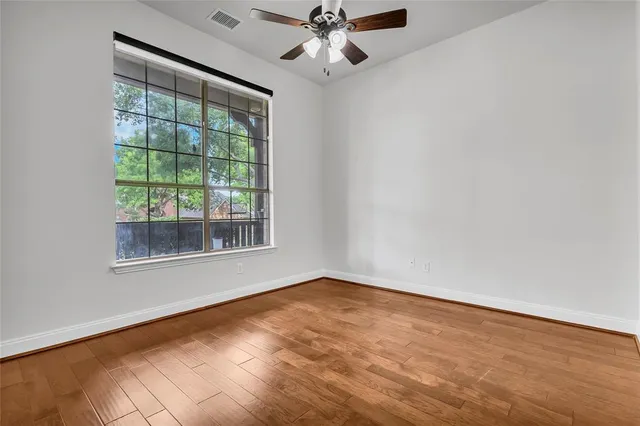 an empty room with a window and ceiling fan