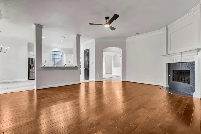 a view of a livingroom with a fireplace a ceiling fan and kitchen view