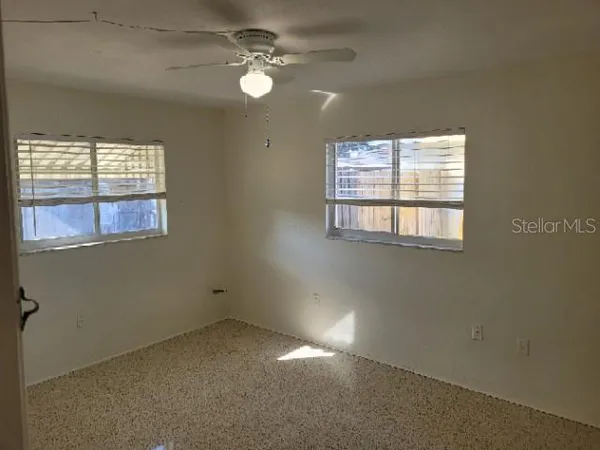 an empty room with windows and fan
