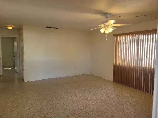 an empty room with a chandelier fan and windows