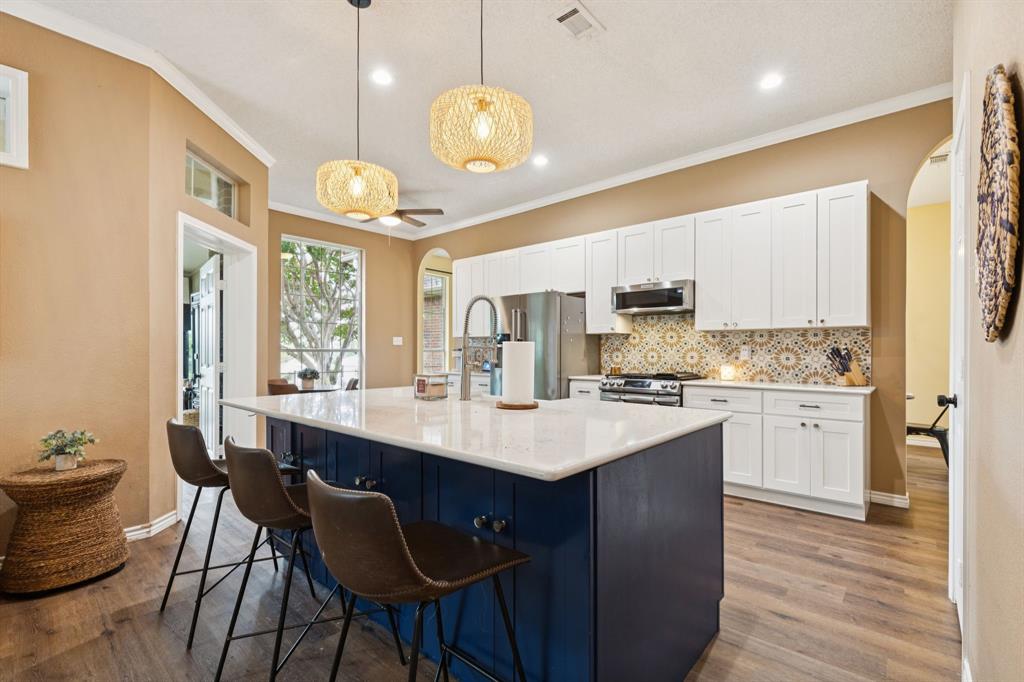 13768 Stirrup Court Forney, TX 75126 - Photo 6 of 32 a kitchen with a stove a sink dishwasher a kitchen island with wooden cabinets and floor