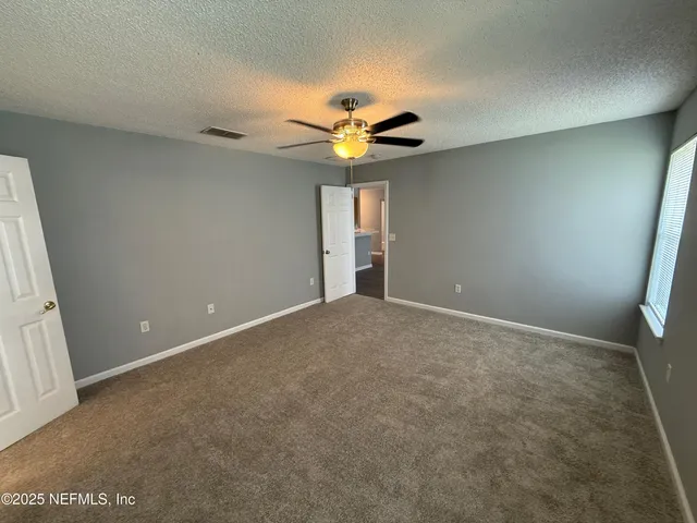an empty room with a window and a ceiling fan