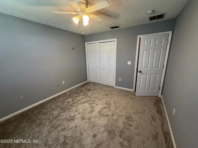an empty room with a chandelier fan and entryway