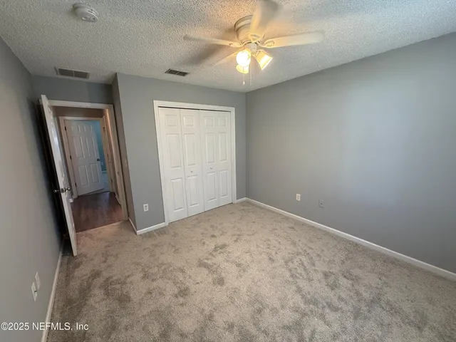 an empty room with windows and fan