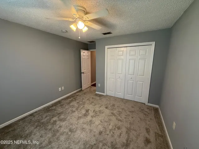 a view of an empty room and chandelier fan