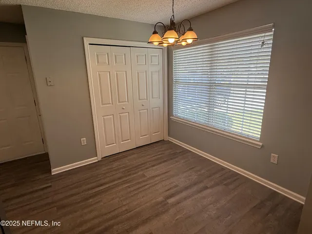 an empty room with wooden floor chandelier and window