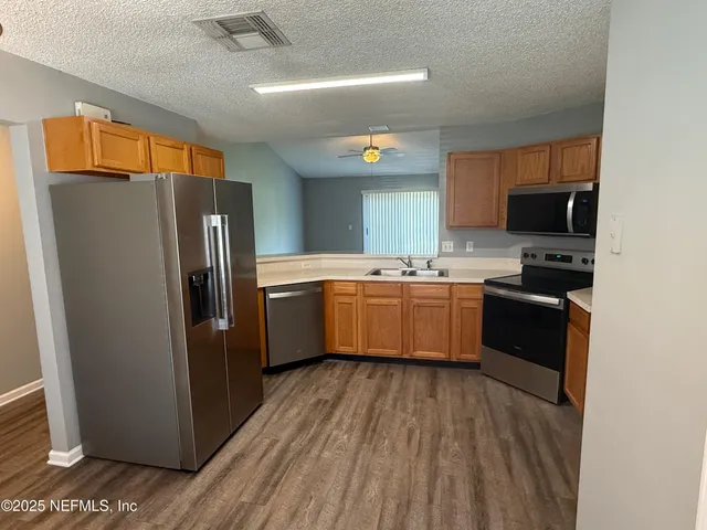 a kitchen with stainless steel appliances a refrigerator a sink a stove top oven a kitchen island and blue cabinets