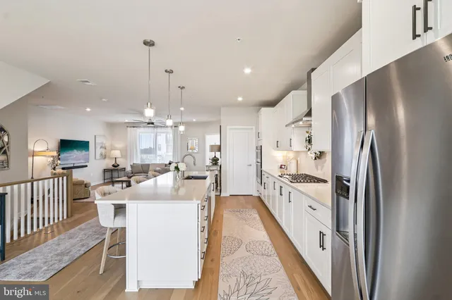 a kitchen with stainless steel appliances granite countertop a sink a stove a refrigerator and chairs