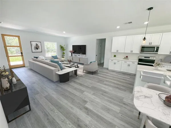 a living room with furniture kitchen view and a wooden floor