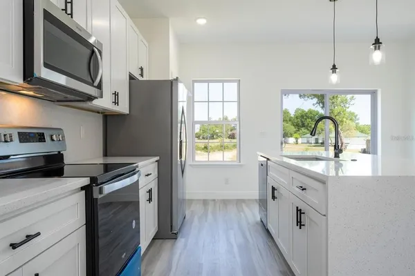 a kitchen with stainless steel appliances granite countertop a stove a sink and a microwave
