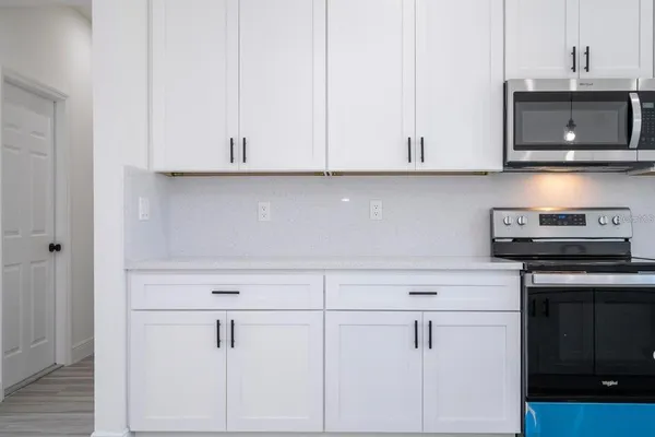 a kitchen with stainless steel appliances granite countertop white cabinets and a stove top oven