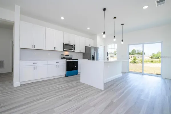 a large kitchen with cabinets wooden floor and a sink
