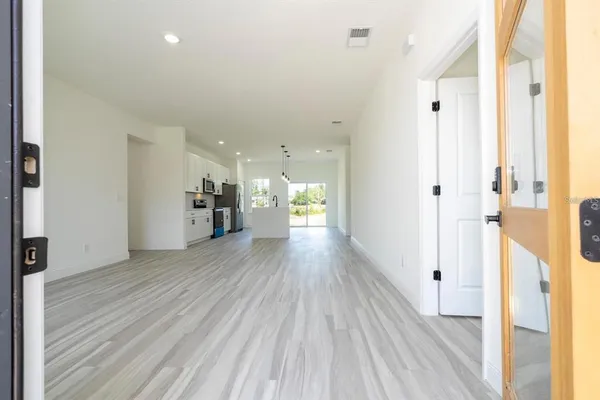 a view of a hallway with wooden floor and a bathroom