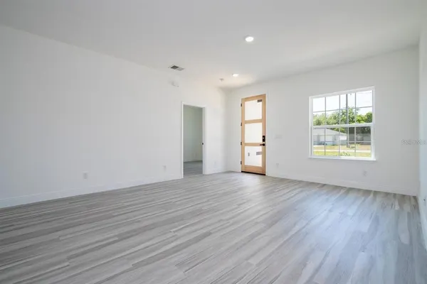 an empty room with wooden floor and windows