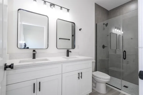 a bathroom with a toilet sink double vanity and mirror