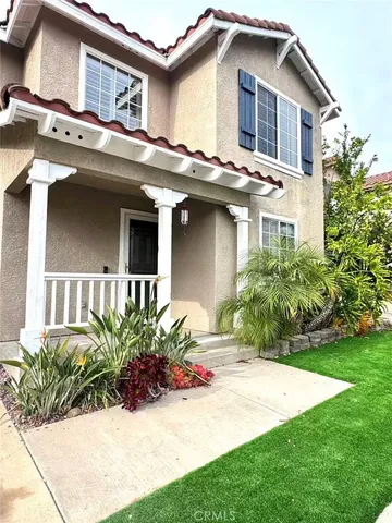 a front view of a house with a yard and potted plants