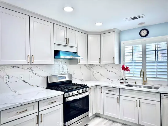 a kitchen with granite countertop a sink stainless steel appliances and cabinets