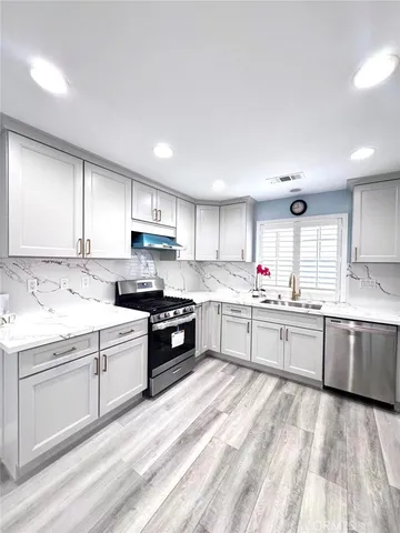 a kitchen with granite countertop a sink stainless steel appliances and cabinets