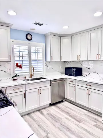 a kitchen with stainless steel appliances granite countertop a sink and cabinets with wooden floor