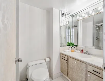 a bathroom with a granite countertop sink mirror vanity and toilet
