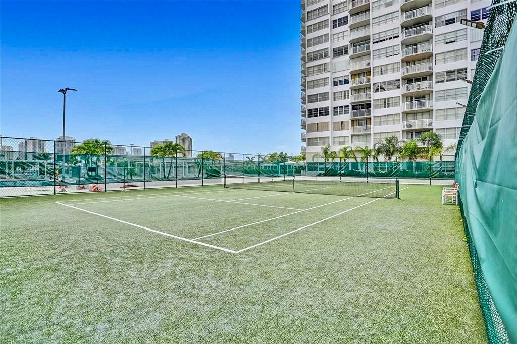 18031 Biscayne Boulevard, Unit 1104 Aventura, FL 33160 - Photo 28 of 35 a view of a tennis ground with large trees