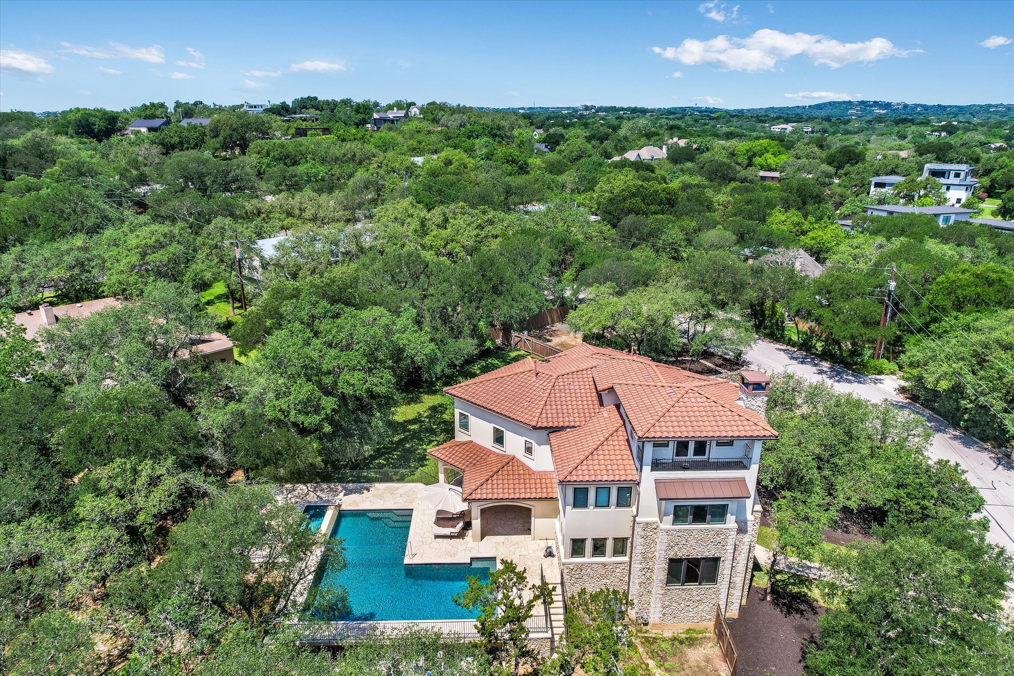 11 Inwood Circle Austin, TX 78746 - Photo 2 of 38 An aerial perspective reveals a luxurious residence nestled among mature trees, complete with a sparkling in-ground pool.