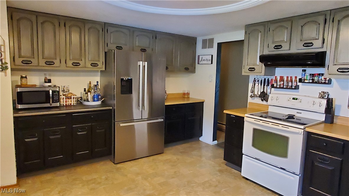 13075 Conquer Hill Road Byesville, OH 43723 - Photo 10 of 36 Kitchen featuring appliances with stainless steel finishes, under cabinet range hood, glass top stove, light countertops, and light floors