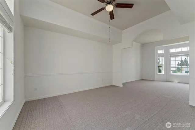 an empty room with a chandelier fan and windows