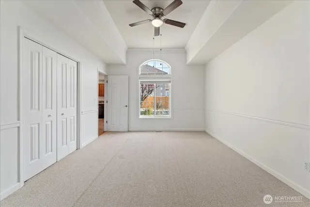 an empty room with chandelier fan and windows