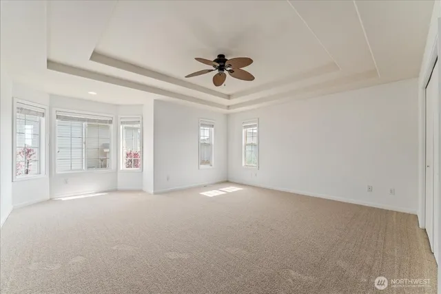 an empty room with chandelier fan and windows