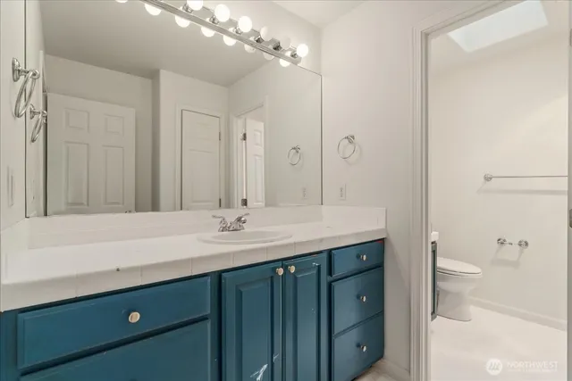 a bathroom with a granite countertop sink a toilet and a large mirror