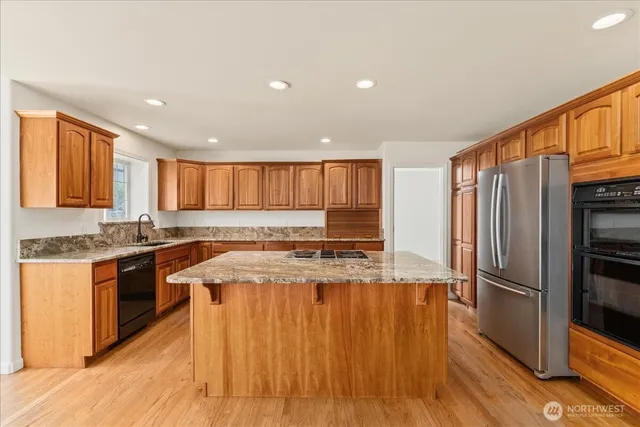 a large kitchen with wooden floor and stainless steel appliances