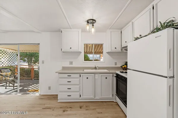 a kitchen with granite countertop a refrigerator a sink and white cabinets
