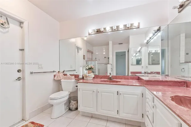 a spacious bathroom with a granite countertop sink a toilet a mirror and shower
