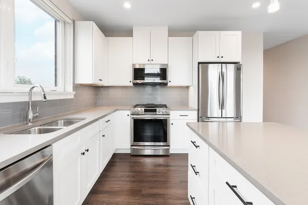 a kitchen with granite countertop a refrigerator stove top oven and sink