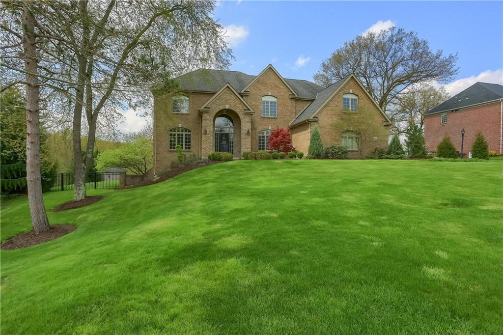 a view of a big house with a big yard and large trees