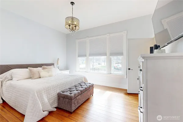 a spacious bedroom with a bed a chandelier and a window